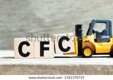 Toy forklift hold letter block c to complete word CFC (abbreviation of Chlorofluorocarbon) on wood background