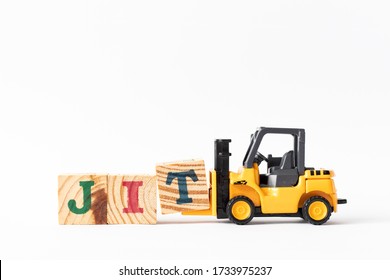 Toy forklift hold wood letter block T to complete word JIT (Abbreviation of Just in time) on white background