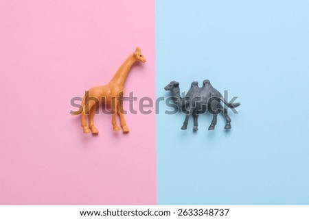 Toy giraffe and camel on blue pink background