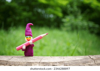 A toy gnome with a pencil in his hands.