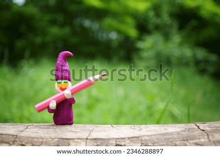 A toy gnome with a pencil in his hands.