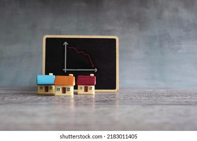 Toy House And Chalkboard With Downward Arrow Graph. Home Sales Market Decrease Loss Concept.