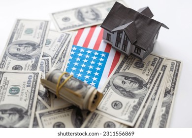 A toy house made of wood with a roof costs money, on a hundred-dollar bill. Concept: mortgage, purchase, sale of real estate, rental housing. - Shutterstock ID 2311556869
