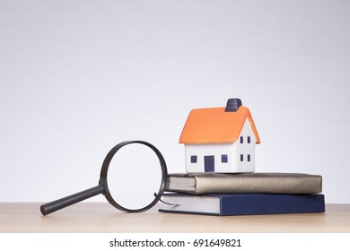 Toy house, magnifying glass and books in a concept of market research when purchasing a property and reading the fine print