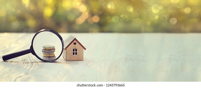toy house, magnifying glass and coins. concept of mortgage, construction, rental housing.  home realtor, business, economics, investments, risks. finding investment sources, sponsors