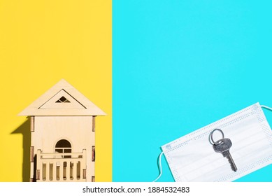 Toy House And Metal Key Lying On Medical Mask, Top View. Multicolored Background, Copy Space. Concept Of Loss Real Estate During The Coronavirus, Eviction Of Tenant