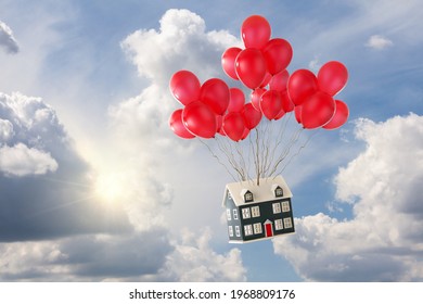 Toy house with red balloons floating in the blue sky with sunshine and white fluffy clouds. Soaring house princes and moving home concept