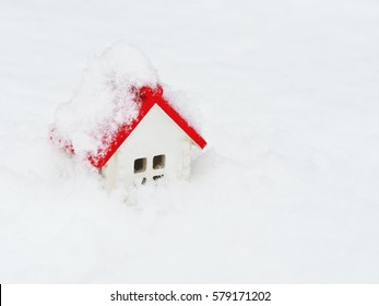 Toy House In Winter, Snow Background. Model Of A Small White Home With A Red Roof Under The Snow