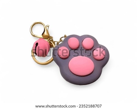 A toy key chain in the shape of a cat paw with a bell isolated on white