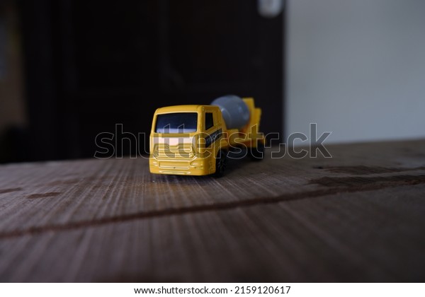 toy mixer truck on wood.\
yellow mixer truck toy with a gray mixer. taken from a landscape\
angle.