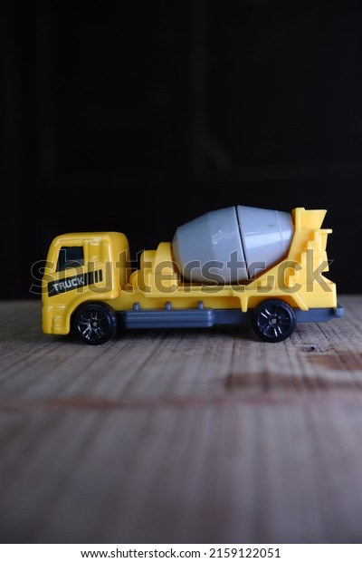 toy mixer truck on wood.\
yellow mixer truck toy with a gray mixer. taken from a portrait\
angle.