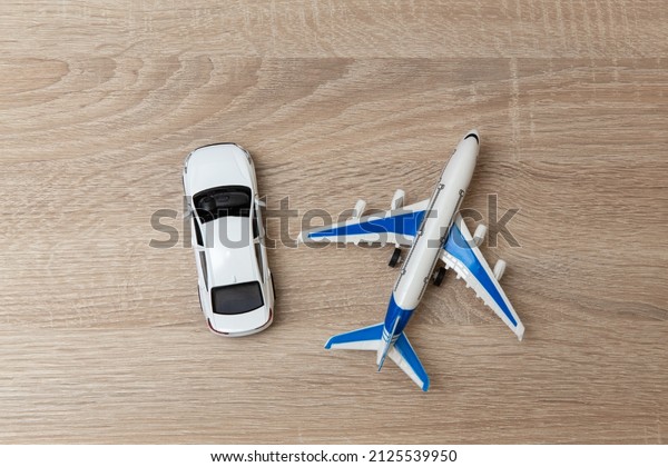 Toy model of a car and a passenger plane on a\
wooden table. Travel\
concept