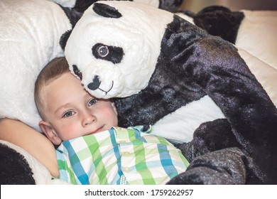 A Toy Panda Hugs A Boy With Wet Eyes. A Porter Of A Child Who Is Crying In A Toy Store. Close-up.