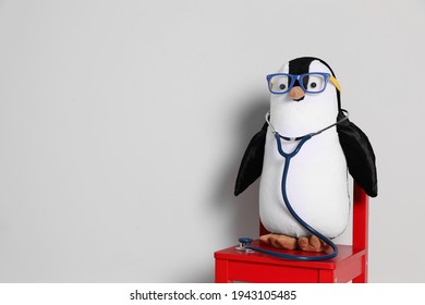 Toy penguin with eyeglasses and stethoscope on white background, space for text. Pediatrician practice