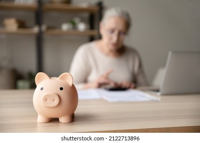 Toy Pink Piggy Bank On Work Table Of Senior Tenant, Homeowner Woman. Elderly Lady Using Calculator, Counting Savings, Taxes. Finance Management, Financial Insurance, Personal Budget Concept