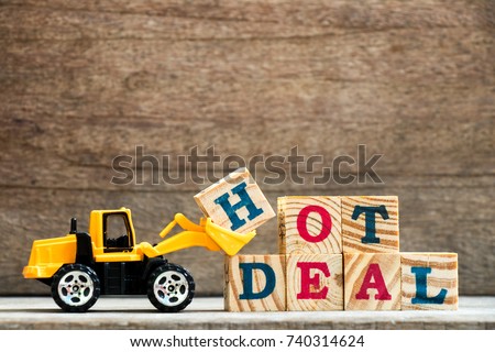 Toy plastic bulldozer hold letter block H to complete wording hot deal on wood background