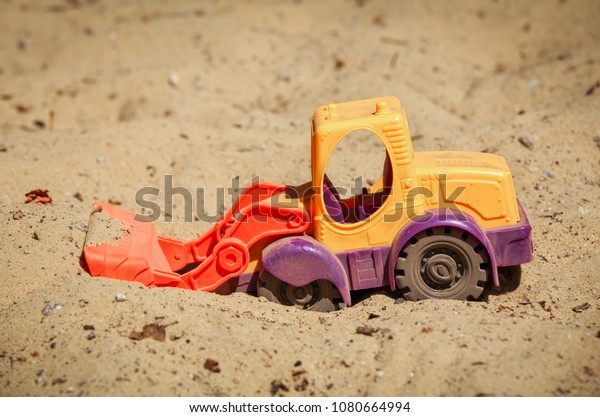 Toy Plastic Bulldozer in the sand. A small
digger on the playground