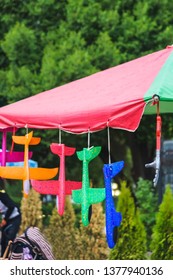 Toy Plastic Planes Of Different Colors. Children's Toy. Bright Planes Of Foam Hanging On The Large Outdoor Umbrella.