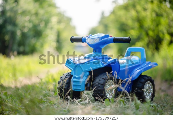 A toy quad\
bike on a green grass\
background.