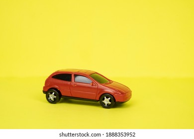 Toy red car close-up on a yellow background. Place for text