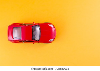 Toy Red Car On The Yellow Background Top View
