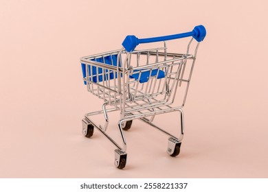 A toy replica of a grocery cart with a blue handle. - Powered by Shutterstock