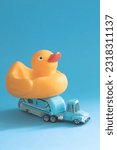 Toy retro caravan car with rubber duck on a blue background. Concept of family summer vacation and travel by trailer. Minimalistic summer retro composition with children