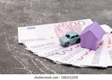 Toy Rhouse And Little Retro Car On A Bundle Of 500 Euro Bills, Black Background, Buying A Car And Real Estate Concept