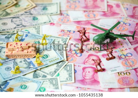 Toy set, tank, soldiers and helicopter placed on US banknotes, dollar currency pile and china banknotes, yuan currency. business and economy war. new world war from business and economy concept.
