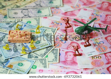 Toy set, tank, soldiers and helicopter placed on US banknotes,dollar currency pile and china banknotes, yuan currency. business and economy war. new world war from business and economy concept.