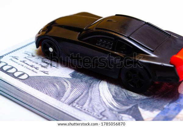 A toy\
sports car in black with a red wing on a springboard, a podium made\
of dollar bills. Car and dollars. Buying, selling price increases\
in the market July 2020. Los\
Angeles.USA