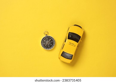 Toy taxi car model with compass on yellow background. Navigation, gps - Powered by Shutterstock