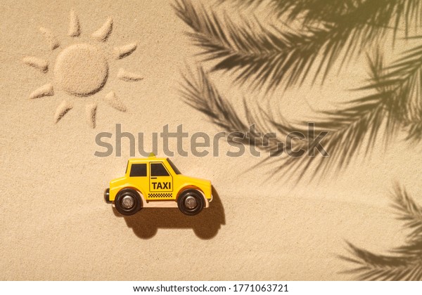 Toy\
taxi car, sun, palm tree on beach sand. Concept. Fast and cheap\
taxi booking service. Travel. Summer time.\
Creative