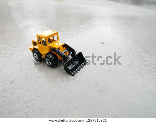 Toy tractor on concrete. Model of the tractor\
on the concrete.