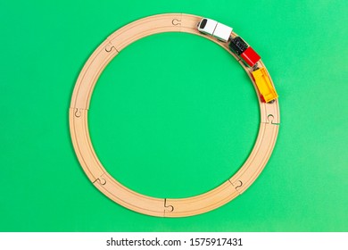 Toy Train Moves On Round Wooden Railways On Light Green Background. Top View