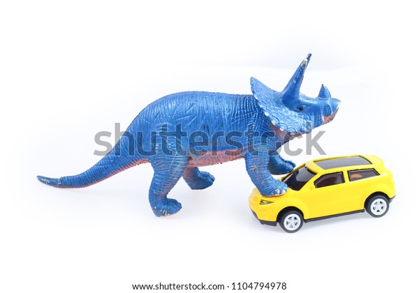 Toy triceratops dinosaur attack yellow car\
isolated on white\
background\
