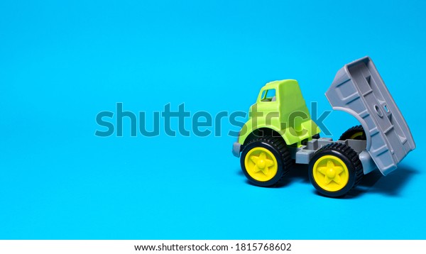 Toy truck car on a blue\
background - construction equipment for children. Bright children\'s\
plastic toys, dump truck childhood. Copyspace banner place for\
text