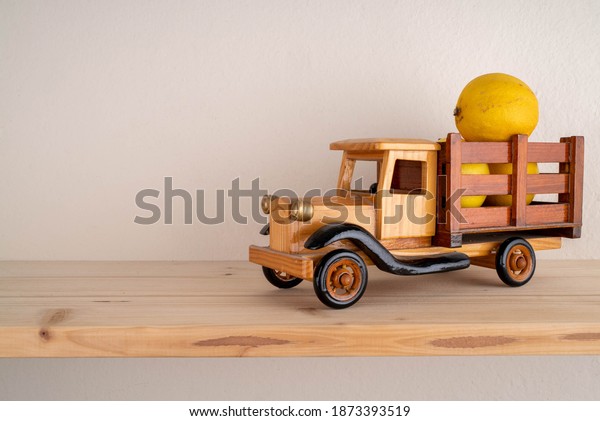 toy truck\
carrying lemons in front of a white\
wall