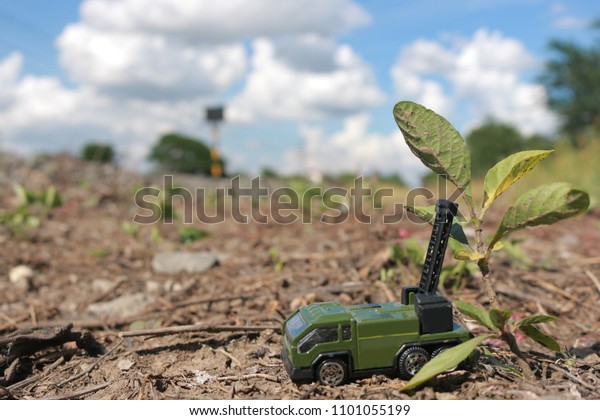 Toy Truck and Construction machinery green Plow\
the tree with on Rough terrain and sand in blur nature tree bright\
light And the sky is\
cloudy.