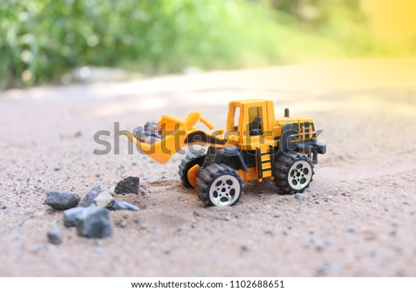 Toy Truck and\
Construction machinery yellow  with Sand and Soil Pile of stones   \
on rough area And the pile of construction machinery is working\
construction concept environment\
