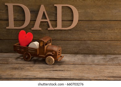 Toy truck with red heart against text dad on wooden plank - Powered by Shutterstock