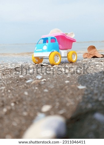 a toy truck sand is on the beach carrying a load of shells