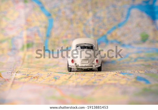 A toy white car with a heart for traveling on the\
map. Creative concept of tourism and road trip. St Petersburg,\
Russia - 8 Feb 2021