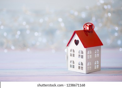 Toy White House With Red Roof And Hole In Form Of Heart On Light Bokeh Background. Romantic Card. Valentine Day Banner.