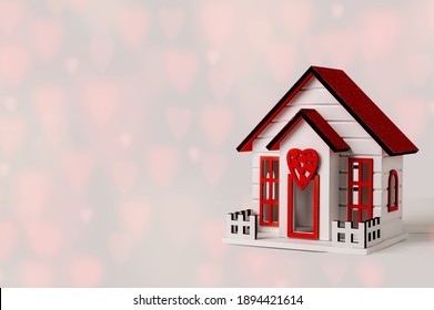 Toy wooden house, on a bokeh background in the form of a heart. Valentine's Day holiday concept.