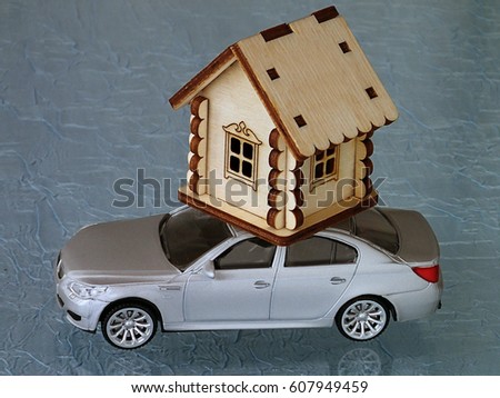 Toy wooden house on the roof of a toy car