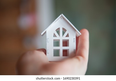 Toy wooden house whiteToy wooden house of white color is in the hand close-up. The concept of stay at home. Quarantine, epidemic  close-up. The concept of stay at home. Quarantine, epidemic