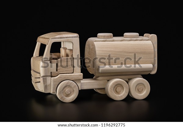 Toy,\
wooden truck with tank, car with  tank for the transport of gas,\
oil. Dark background, copy space, studio\
shot.