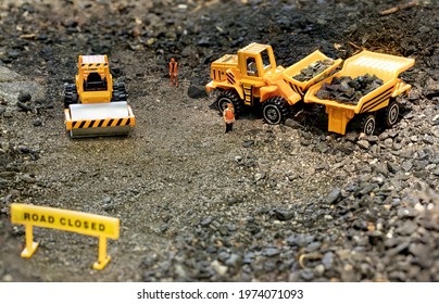 Toy workers in road construction diorama load rocks into haul truck. - Shutterstock ID 1974071093