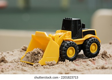 Toy Yellow Bulldozer With Sand On Children's Sandbox, Trucks Concept, Closeup